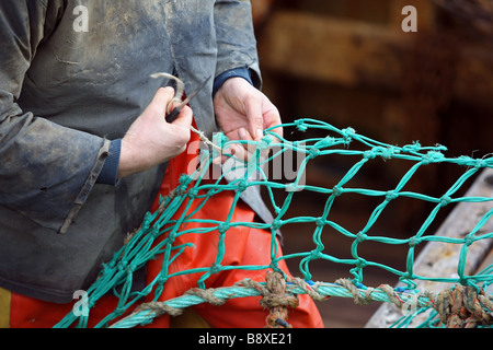 North Sea fishermen mending and repairing fishing nets in the harbour at Peterhead, Aberdeenshire, Scotland, UK Stock Photo