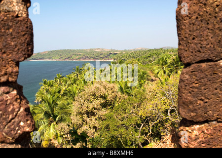 View on tropical beach covered with palm trees through castle wall. Stock Photo