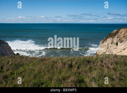 View from the rocky crumbling cliffs above the Crashing waves of the Pacific Ocean looking west Stock Photo