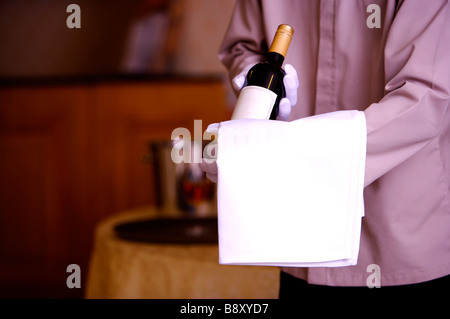 Young waiter holding a bottle of red wine Stock Photo