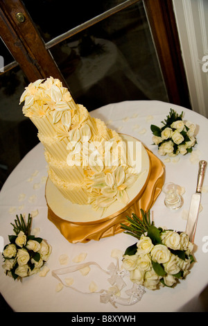 Four-tier white chocolate wedding cake decorated with icing roses and white flowers. Stock Photo