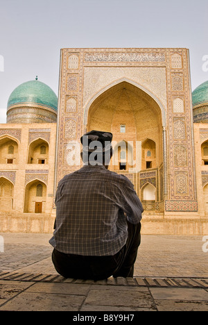 Man sitting down in front of the Mir-i-Arab medressa, Bukhara, Uzbekistan, Asia Stock Photo