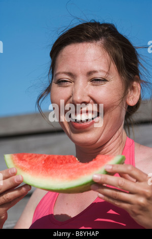 A woman eating a water melon Sweden.