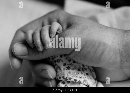 Newborn baby's hand in the hand of his mother and a black and white picture Stock Photo