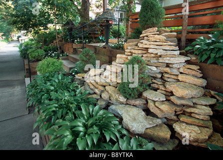 STACKED ROCK, HOSTAS AND FENCE IN FRONT OF MINNEAPOLIS, MINNESOTA HOME.  SUMMER. Stock Photo