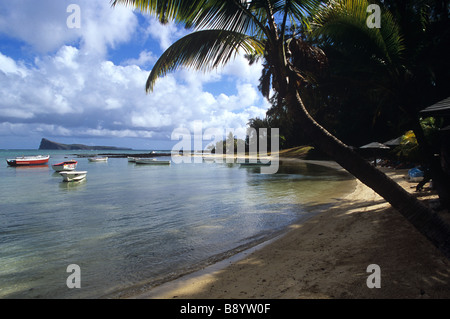 A peaceful beach at Cap Malheureux, Mauritius with boats palm tree and the island of Coin de Mire. Stock Photo