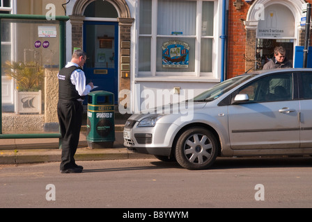 A police community support officer cso issuing a parking ticket on an illegally parked car in the uk Stock Photo