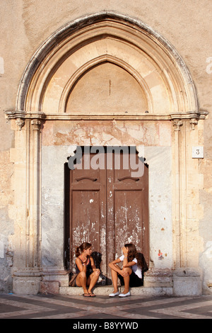 2 Girls sat in a church doorway in Piazza IX Aprile Taormina Sicily Stock Photo