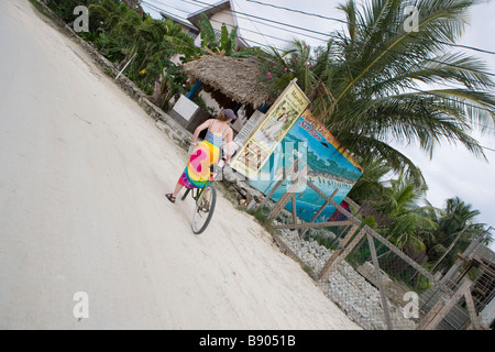A young woman rides her bicycle along the beaches of San Pedro on Ambergris Caye in Belize. Stock Photo