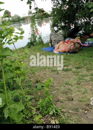 Two festivalgoers sleeping by a lake during The Secret Garden Party 2008, UK Stock Photo