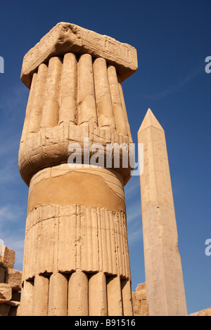 Close up detail of stone carved papyrus column with obelisk of Queen Hatshepsut in background, Karnak Temple, Luxor, Egypt Stock Photo