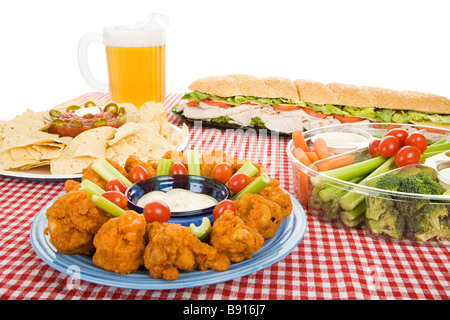 Table set with a variety of party foods and a pitcher of beer White background  Stock Photo