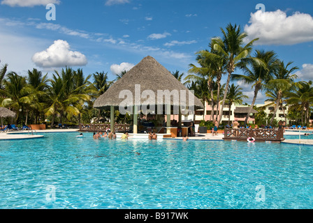 Hotel swimming pool thatch pool bar Bayahibe Dominican Republic Viva Wyndham Dominicus Palace all-inclusive resort palm trees Stock Photo