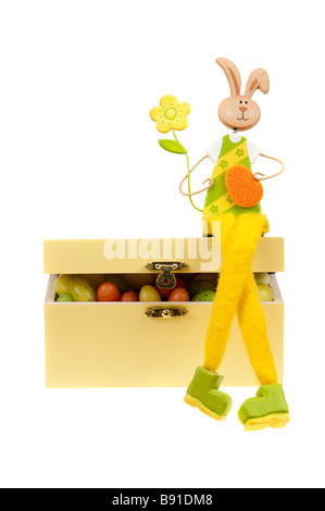 Easter bunny on a box full of easter eggs isolated on white Stock Photo