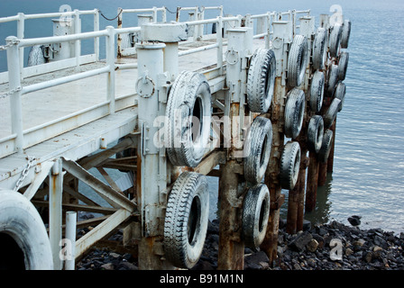 Worn white painted tire bumpers on passenger boat loading pier on shores of Sea of Galilee lowest freshwater lake in world Stock Photo