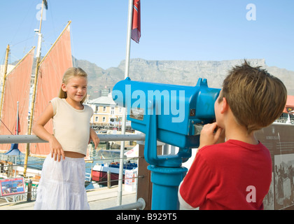 Boy looking at girl through telescope, Cape Town, Western Cape Province, South Africa Stock Photo