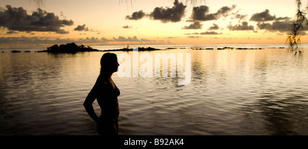 A tourist observes the sunset over rocky outcrops in Mauritius Stock Photo
