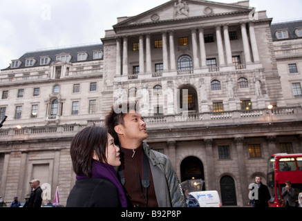 Asian oriental tourist couple in 20s / 30s visiting London, outside of Bank of England in City of London Stock Photo