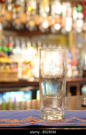 empty pint glass of beer sitting on bar in a pub Stock Photo