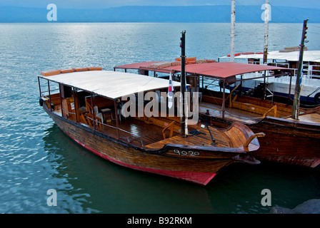 Old wooden Tiberiade replica Jesus tour boats tied up at dock in Sea of Galilee at dawn Stock Photo