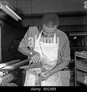 A black worker, part of the 'Windrush generation', working on a moccasin in a shoe factory, Leicester, c. 1959