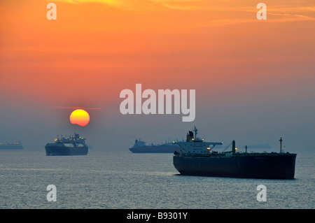 Sunset haze & shipping including unladen bulk carriers & oil tankers coastal anchorage UAE Fujairah bunkering port Gulf of Oman near Straits of Hormuz Stock Photo
