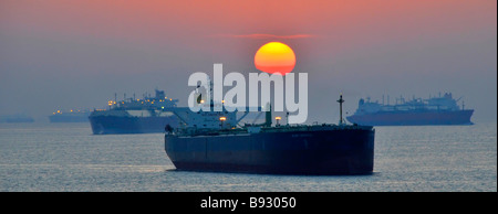 Sunset haze & shipping including unladen bulk carriers & oil tankers coastal anchorage UAE Fujairah bunkering port Gulf of Oman near Straits of Hormuz Stock Photo
