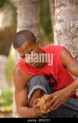 Young Bajan man opening fresh coconut at 'Crane Beach', Barbados, 'West Indies' Stock Photo