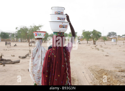 Women carry water in an internally displaced persons (IDP) camp in Goz Beida, Eastern Chad, Africa Stock Photo