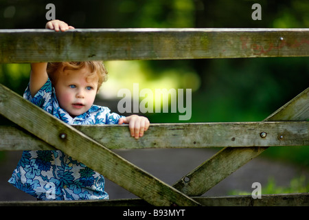 Three year old boy climbing over gate. Stock Photo