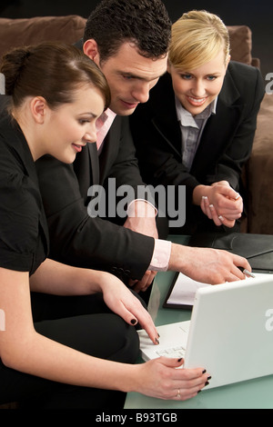 A businessman and his two female colleagues looking at a presentation on a white laptop computer Stock Photo