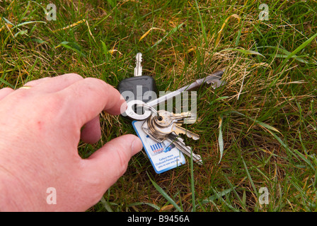 Person picking up a set of car and house keys from the ground Stock Photo