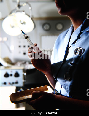 A nurse wearing a blue uniform prepares a hypodermic needle Stock Photo