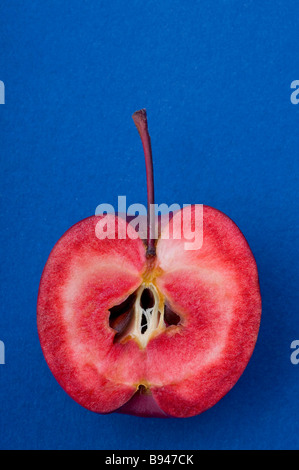 A crab apple cut in half to show the red interior of the fruit Stock Photo