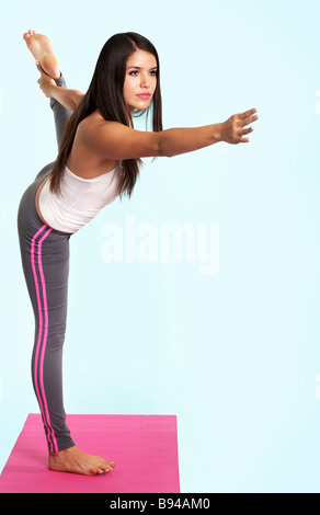 Young woman yoga king dancer pose on pink mat stock photo. Young woman doing yoga king dancer pose indoors Stock Photo