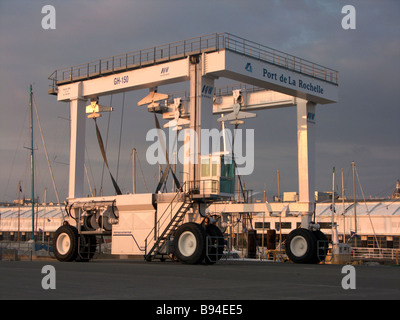 A heavy lift crane in the sea port of La Rochelle for lifting containers from boats and lifting boats seen at sunset Stock Photo