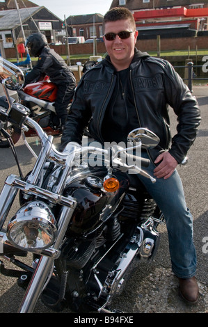 A Harley-Davidson rider wearing a black leather jacket and dark sunglasses, looking at the camera, Rye, East Sussex, England, UK Stock Photo