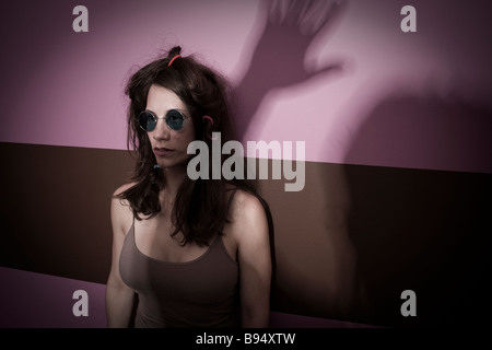 Young woman wearing sunglasses in front of a shadow of a man s hand MODEL and LOCATION RELEASED Stock Photo