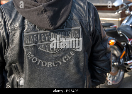 A detail of a Harley-Davidson black leather jacket with a Harley-Davidson motorcycle in the background, Rye, England, UK Stock Photo