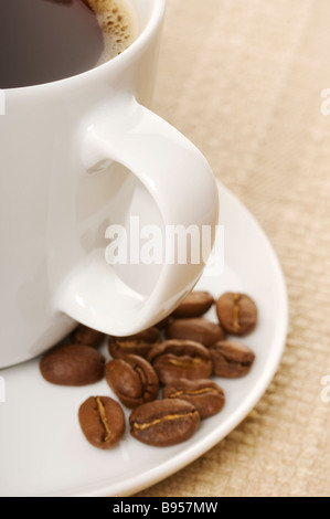 Close up of cup of black coffee and beans in a saucer Stock Photo