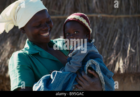 MOZAMBIQUE East Africa People Portrait of laughing young Zimbabwe refugee woman carrying child Stock Photo