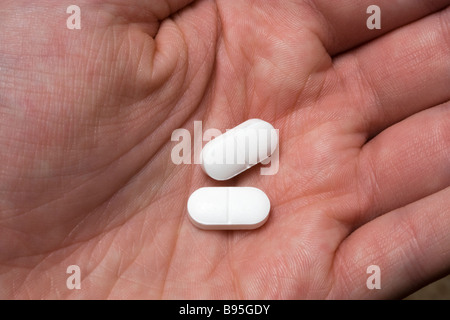 Two painkiller pills in hand