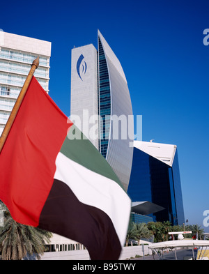 UAE Dubai National Bank of Dubai seen from dhow on Dubai creek with UAE flag in the foreground. Stock Photo