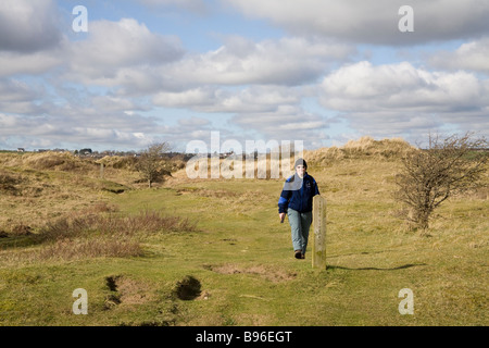 Newborough Anglesey North Wales March A woman walking along a waymarked footpath in Newborough Warren National Nature Reserve Stock Photo