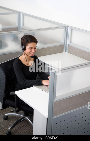Businesswoman talking on headset in cubicle Stock Photo