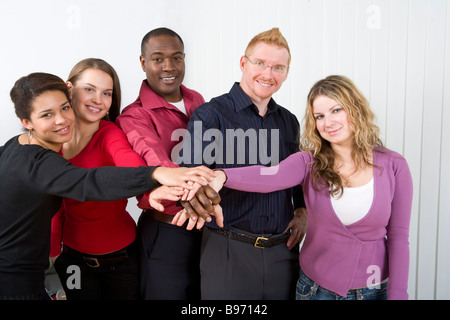 Multi ethnic co workers stacking hands Stock Photo