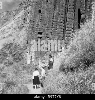 1950s, historical, visitors on a coastal path by a cok, a basalt rock formation at the ancient Giant's Causeway, Co. Antrim coast, Northern Ireland. Stock Photo