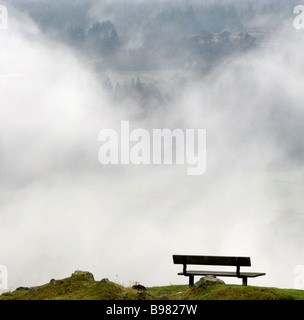 An empty bench facing a descending fog on the Campsie Fells near Glasgow in Scotland Stock Photo