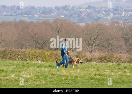 Mature woman walking her German Shepherd dog on the Sussex Downs in early Spring. Stock Photo