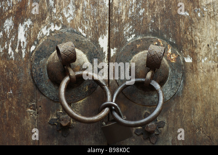 Old wooden doors, close-up of iron door handles linked by padlock